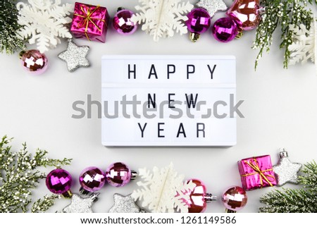 HAPPY NEW YEAR text on lightbox composition and of Christmas decorations on white table background,copy space