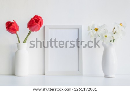 Mockup with a white frame and red tulips in a vase on a light background