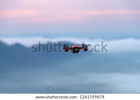 A drone is flying above the mountain with a misty in the morning. 