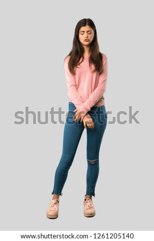 Full body of Teenager girl with pink shirt with sad and depressed expression on isolated grey background