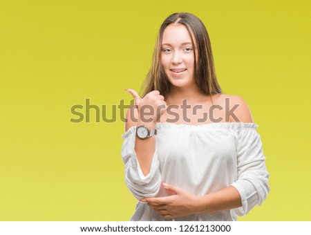 Young caucasian beautiful woman over isolated background smiling with happy face looking and pointing to the side with thumb up.