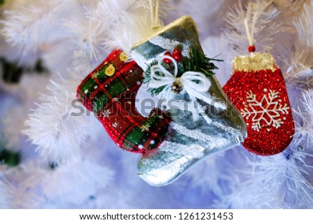 Red Christmas boot with a red mitten on the background of a white Christmas tree, the theme of decorative toys and Christmas
