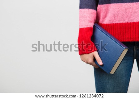 Confident smart  student girl holding book in one hand over white background.Close up of a student hand holding.Confident studying concept.