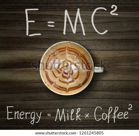 The cup of black coffee with milk and two formulas. E = mc2. Wood background.