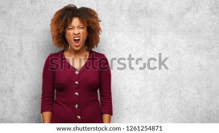 Young black afro woman screaming very angry and aggressive