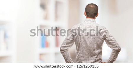 Caucasian man on grey brackground from behind, looking back