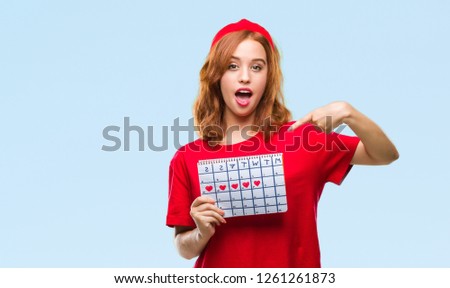 Young beautiful woman over isolated background holding menstruation calendar very happy pointing with hand and finger