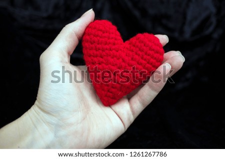 red heart knitted from yarn lies in woman hand. beautiful background