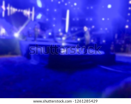 Blurred picture of music band perform on a concert stage with color light shining. Singer hold microphone and walk on stage.