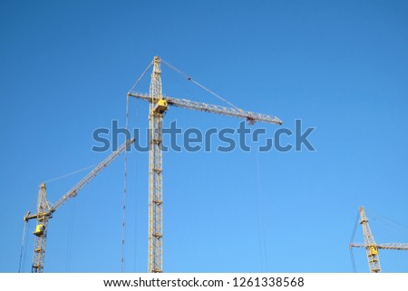 Big yellow construction tower crane over clear blue as background, sky horizontal photo