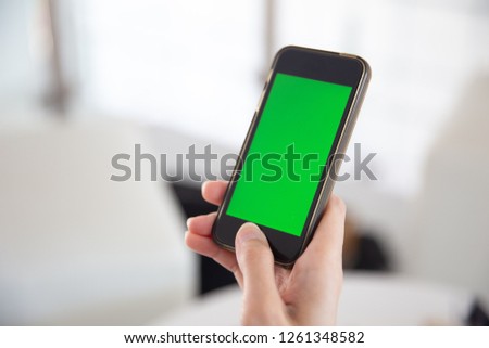 closeup hand hold smartphone with green screen isolated touchscreen.