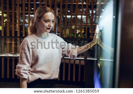 Blonde girl with pink sweater and pigtail looking at fish tank with colorful exotic fishes