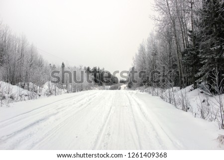 Empty road with huge snow banks on sides on cloudy winter day