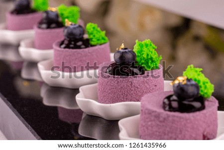 Desserts in white flat dishes on a dark glossy background