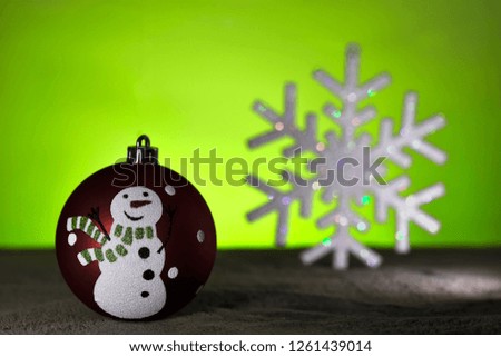 Christmas sphere with a design of a snowman with a tie, in the background an artificial snowflake