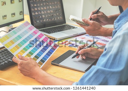 Graphic design with color swatches and tablet on a desk. Graphic designer drawing something on tablet at the office with work tools and accessories.