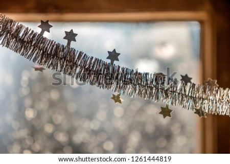 Close-up detail new year Christmas decoration, silver stars and rain on window light blurred bokeh background. Sparkling DIY decoration ideas for New Years Eve celebration party.