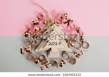 Christmas and New Year's Day festive decoration, wooden Christmas tree with golden ribbons on pink and gray background.  Copy space for text. Flat lay. View from above with text 2019.
