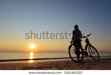 The sunset. Woman with the bicycle on the seaside 
