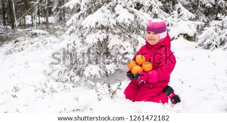 Us snow in red clothes with oranges sits a child under the tree.