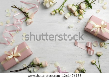 Flat lay composition with beautiful roses and gift boxes on wooden background. Space for text