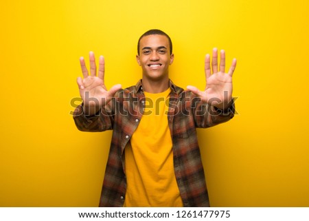 Young african american man on vibrant yellow background counting nine with fingers