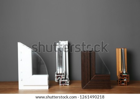Samples of modern window profiles on table against gray wall. Installation service