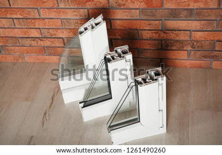 Samples of modern window profiles on floor against brick wall. Installation service