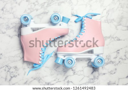 Pair of stylish quad roller skates on marble background, top view