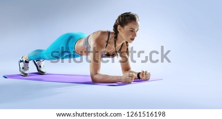 Sport. Young athletic woman doing plank. Muscular and strong girl exercising. Fitness exercising.