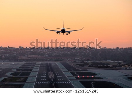 A passenger jet approaches its landing at Lindbergh Field in San Diego California during sunset Royalty-Free Stock Photo #1261519243
