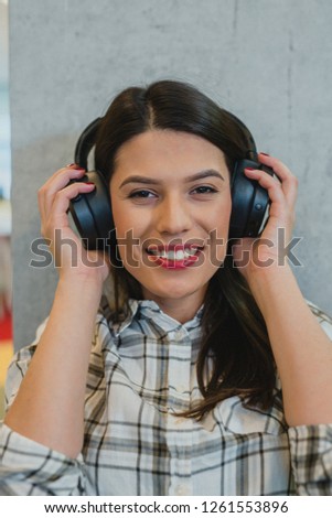 Young beautiful businesswoman listening music in headphones at office