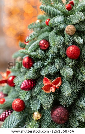 Beautiful small decorated Christmas tree on dark wooden table. Happy mood. Garland bokeh on background. Wallpaper. Danish pine and fir, Nobilis