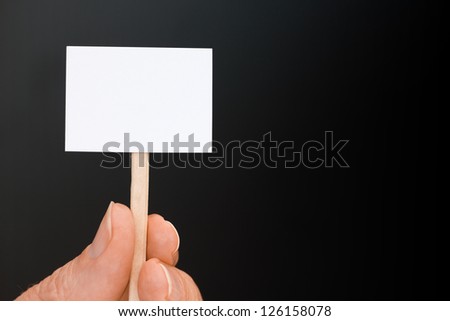 Hand Holding a miniature blank sign on black ready for your text and with extra copy space