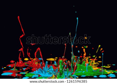 Colored explosions of paint, caused by sound on black background 