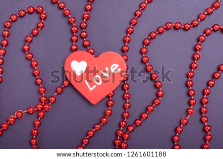 St. Valentine's Day. Concept red heart love symbol on blue paper background with beads ornament
