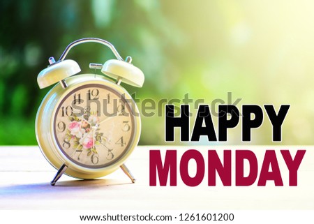 A retro alarm clock on a white table top with nature background and morning sunlight. A text 'Happy Monday' written on image.
