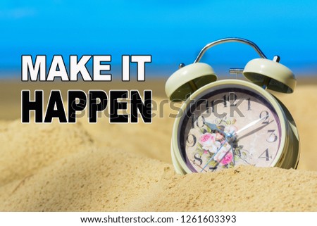 A retro alarm clock on a sand at the beach with blue sea background. A text 'Make it happen' written on image.