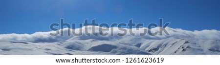 Panoramic photo of a snowy mountain range in the early morning.