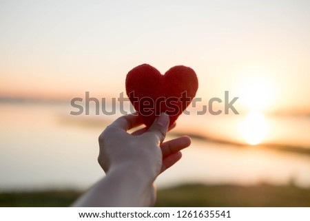 Heart made with hand and the sun is the backdrop.