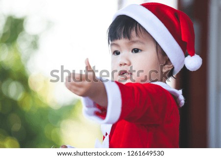 Cute asian baby girl wearing santa suit holding beautiful gift box in hand on Christmas celebration
