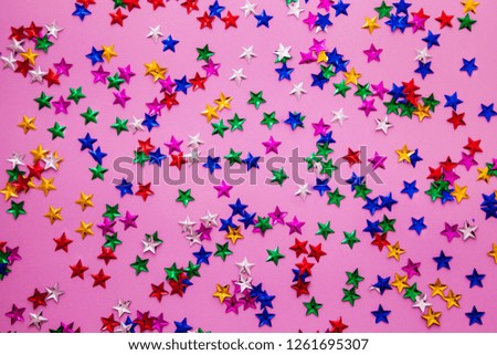 Bright multicolor stars confetti on violet background. Holiday concept.