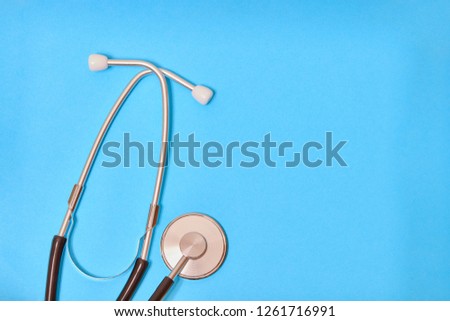 Black stethoscope isolated on blue background