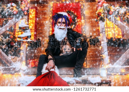 Cool punk Santa fools around near his house with a bag of gifts in his hands.