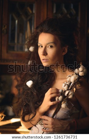 girl with a branch of cotton in the old interior