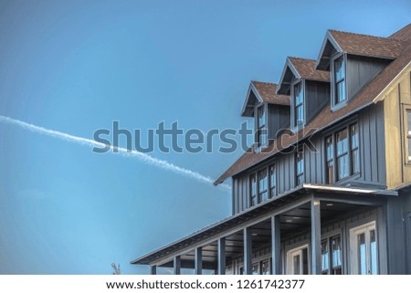 Sunlit home and sky with contrail in Daybreak Utah