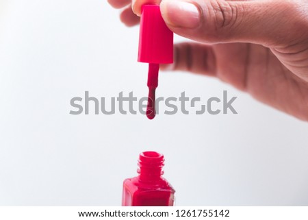 close up of a nail polish bottle and drop on white background