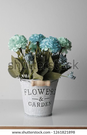 A pot with blue plastic flowers on a white background.