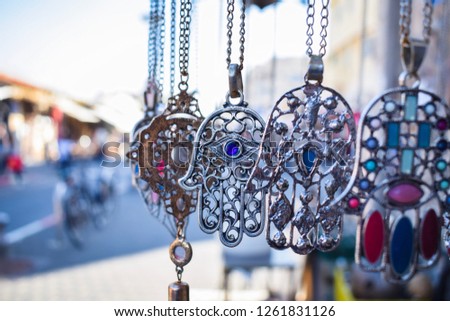 Close-up of Hamsa, also known as Fatima Hand or Hand of God necklace,  pending on a flea market in Tel Aviv-Jaffa, Israel. Metal protection amulet. Royalty-Free Stock Photo #1261831126
