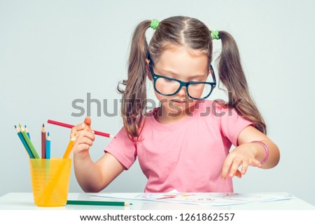 beautiful cute little girl drawing picture on white paper with colorful pencils 